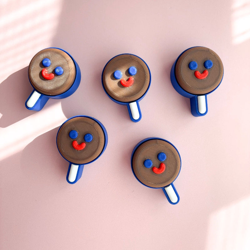 Five ice cream cone-shaped cookies with face designs on a pink background
