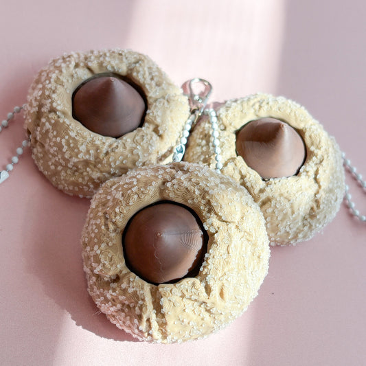 Three cookie-shaped fidget clickers with chocolate centers on a pink background