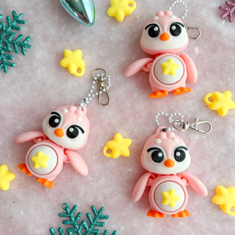 Colorful penguin keychains with snowflake and star decorations on a textured surface.