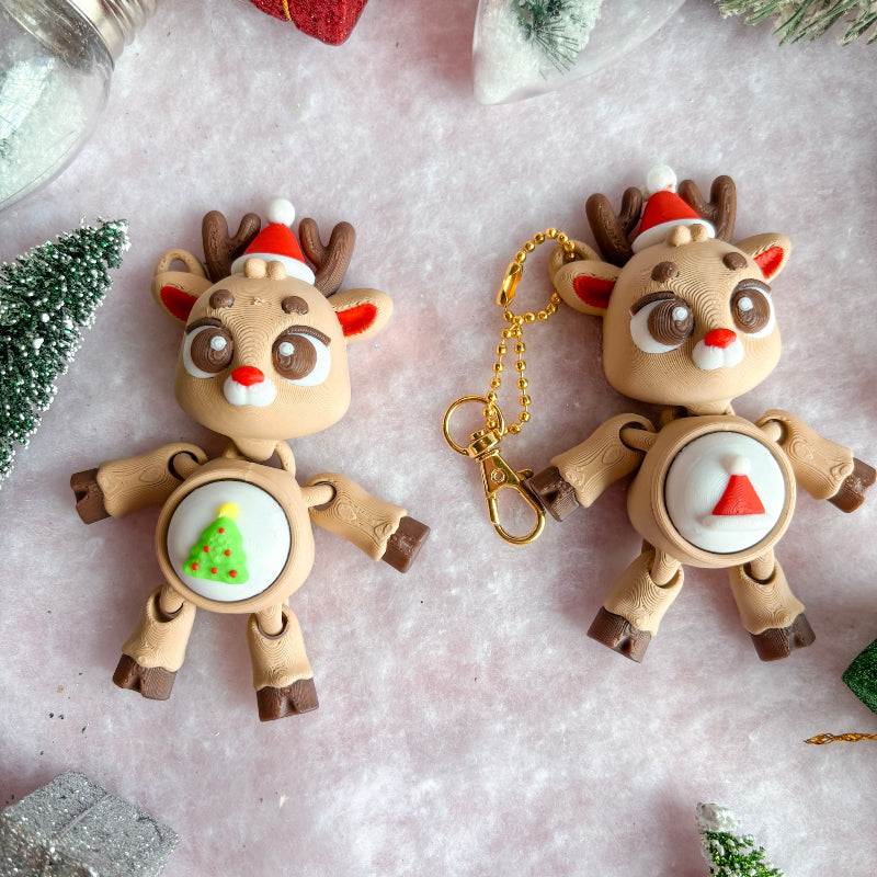 Two reindeer-shaped keychains on a textured surface with Christmas decorations.