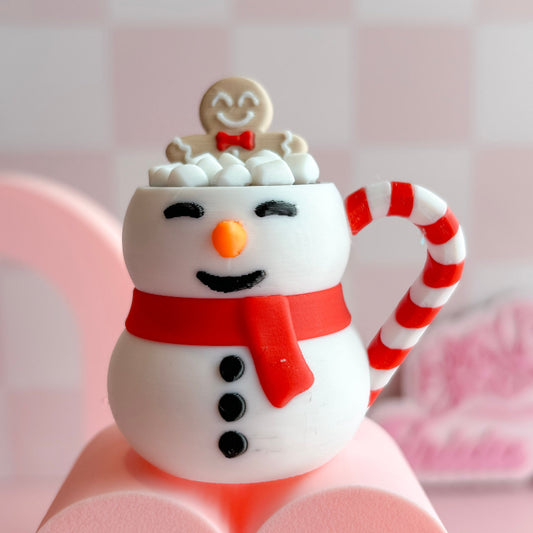 Snowman-themed mug with candy cane handle on a pink background