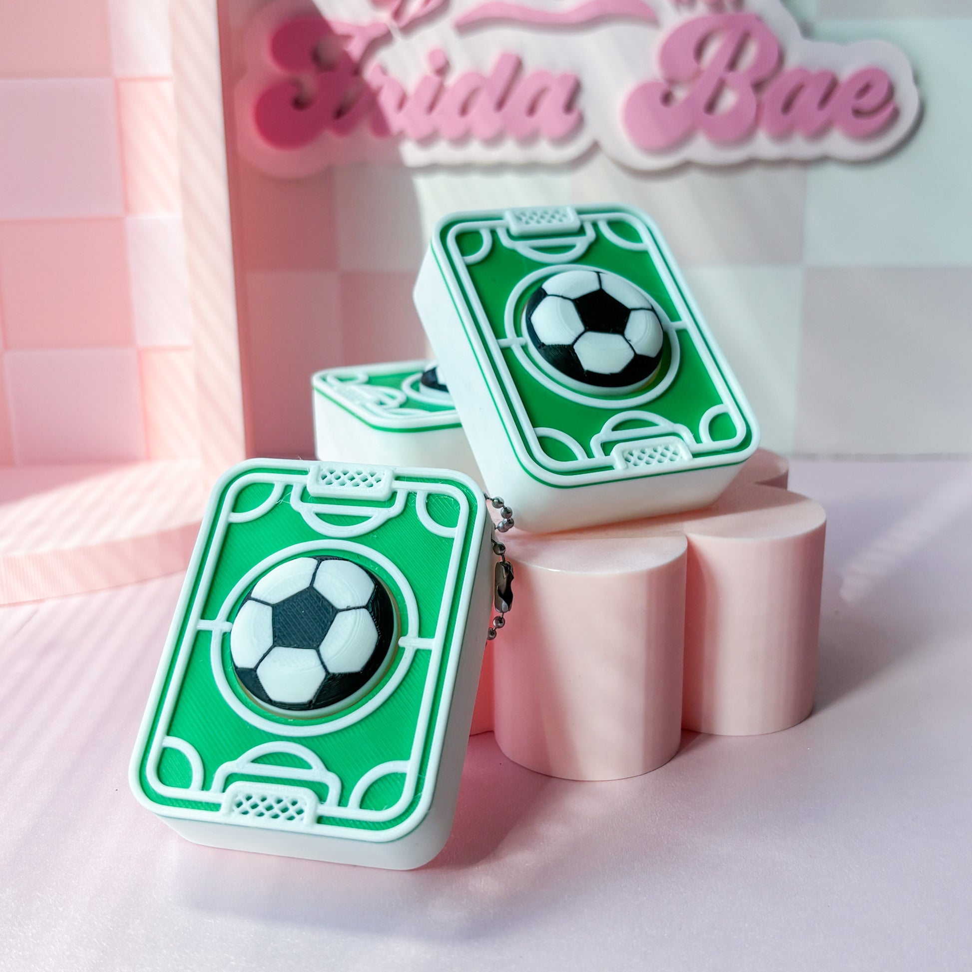 Green card-style fidget clicker with soccer ball design on a pink background