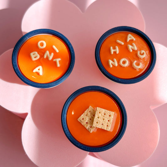 Three small orange containers with blue rims on a pink flower-shaped plate.