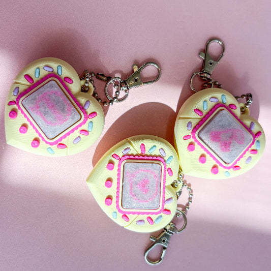 Three heart-shaped keychains with a pink center on a pink background