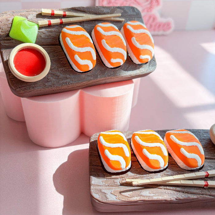 Decorative fidget clicker haped like salmon sushi on a wooden board with a hand holding one cookie.