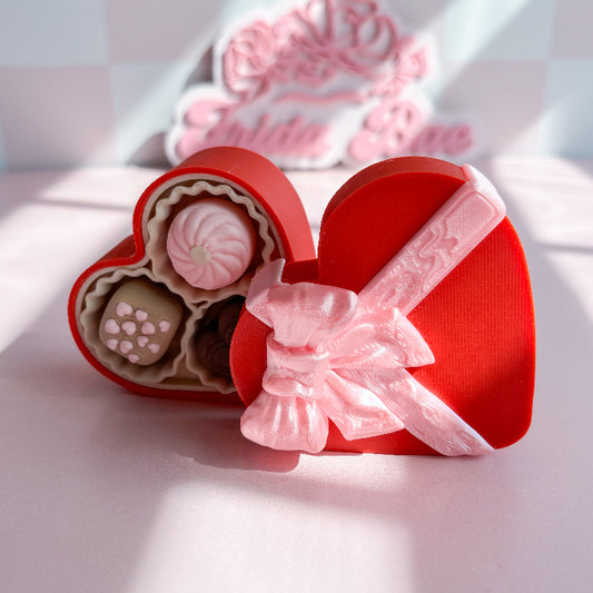 Heart-shaped red gift box fidget clicker with pink ribbon and pink and white candies on a light background
