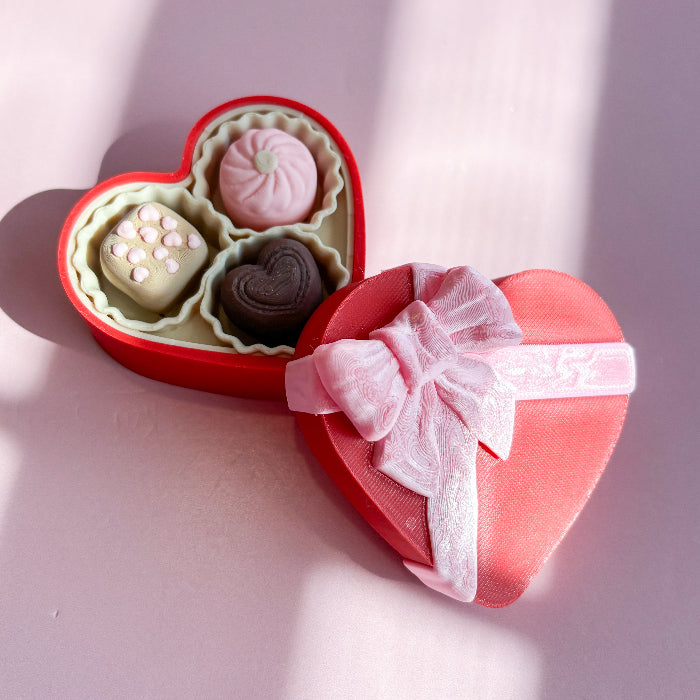Sweetheart_Fidget_Clicker Heart-shaped gift box with pink ribbon and assorted chocolates on a light pink background