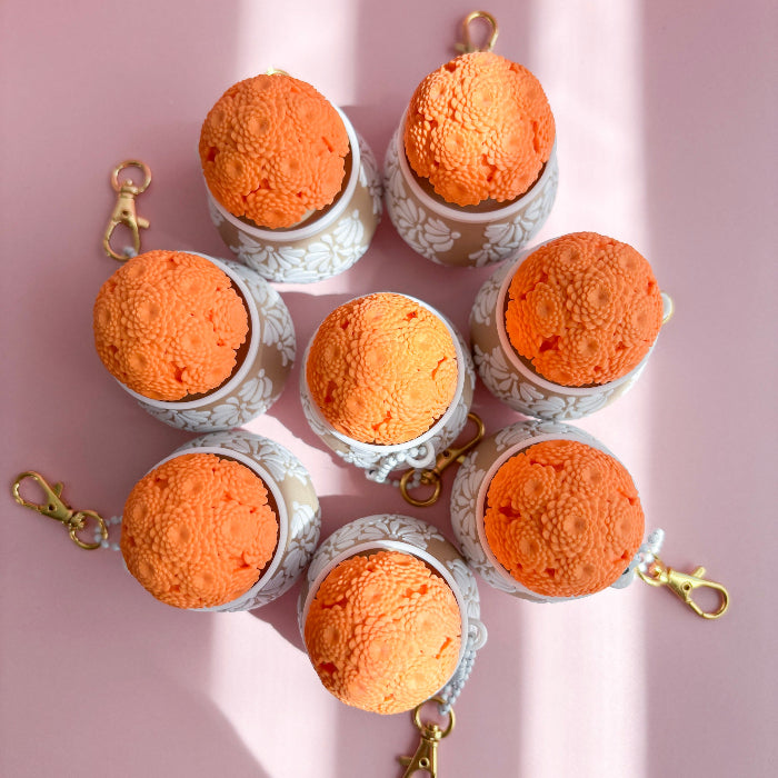 Orange ice cream keychains arranged in a circular pattern on a pink background