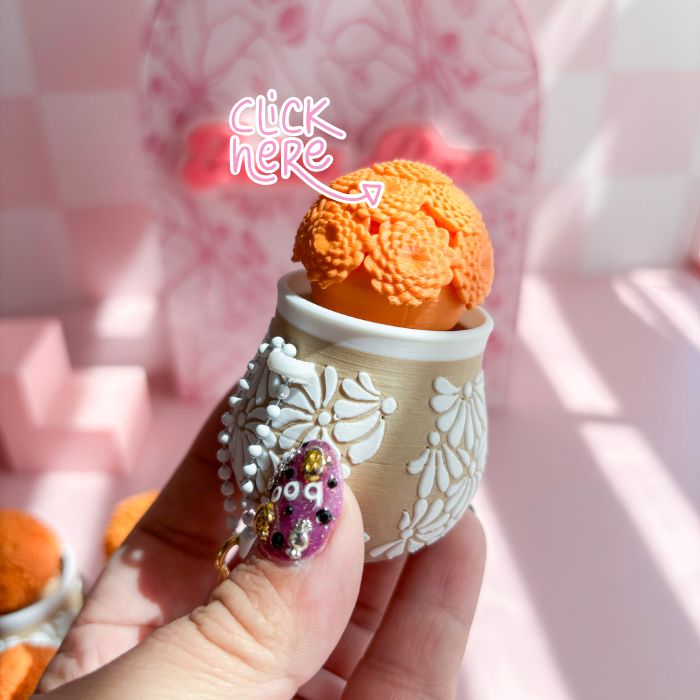 Hand holding a small decorative cup with orange ice cream against a pink checkered background