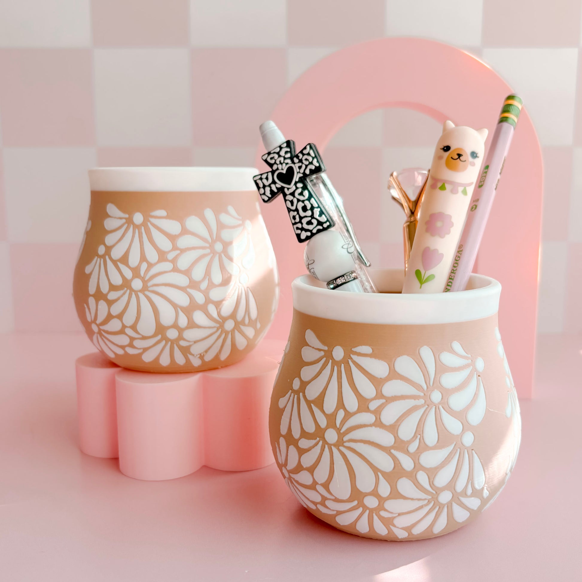 Two 3D printed pen holders with floral patterns on a pink background