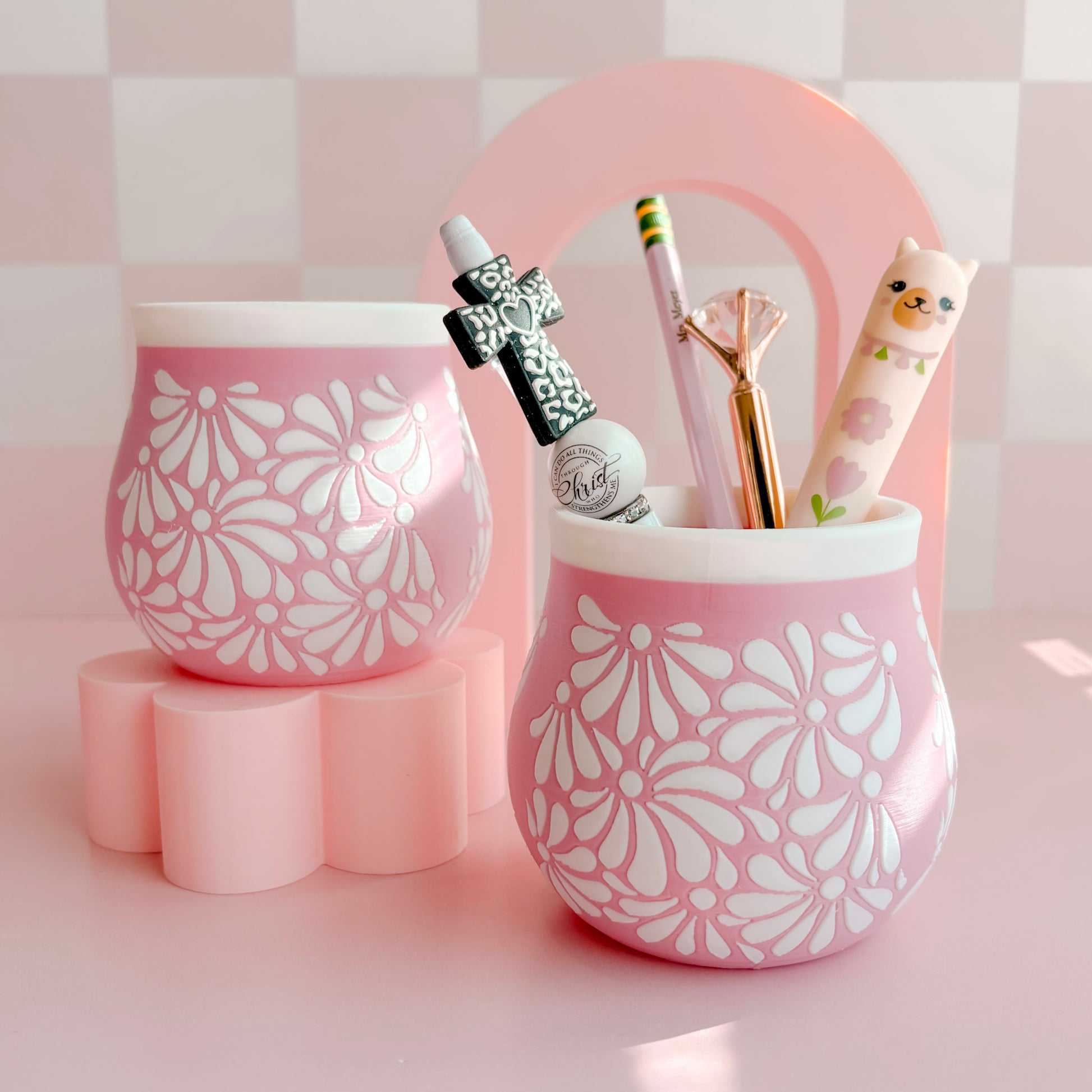 Two 3D printed pen holders with floral patterns on a pink background
