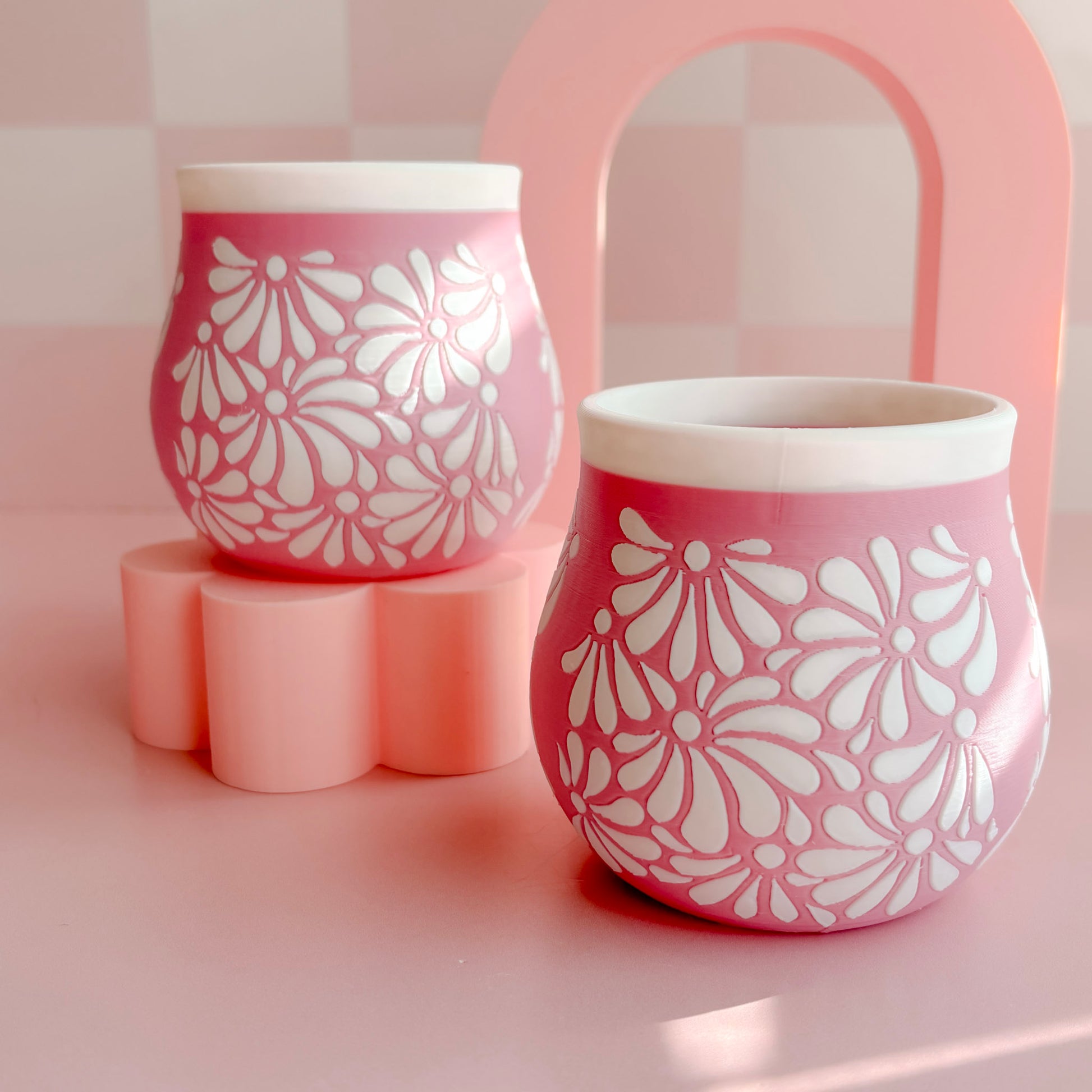 Two 3D printed pen holders with floral patterns on a pink background