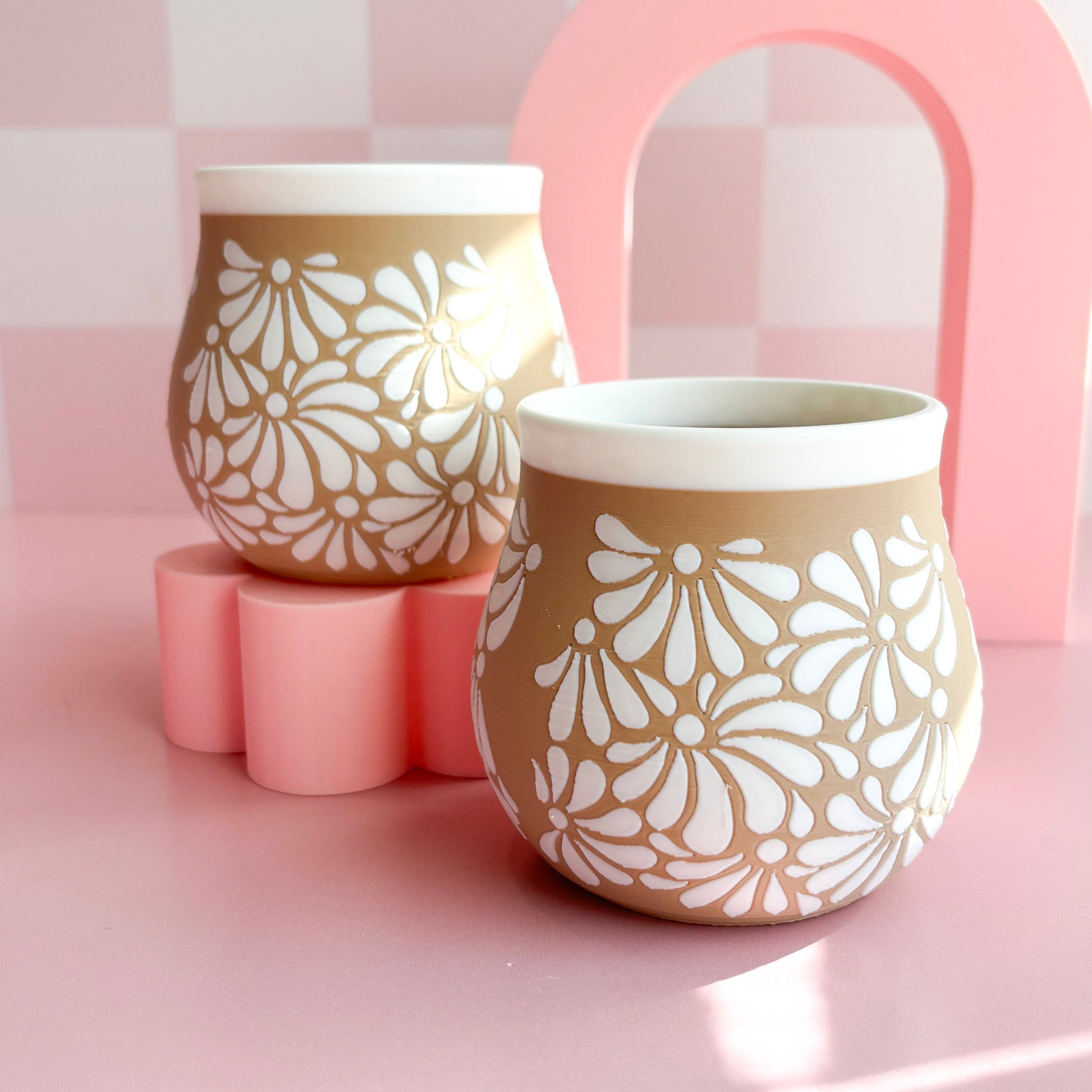 Two 3D printed pen holders with floral patterns on a pink background