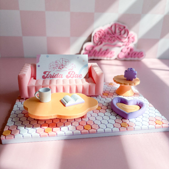 Miniature pink sofa set with decorative items on a pink and white checkered background