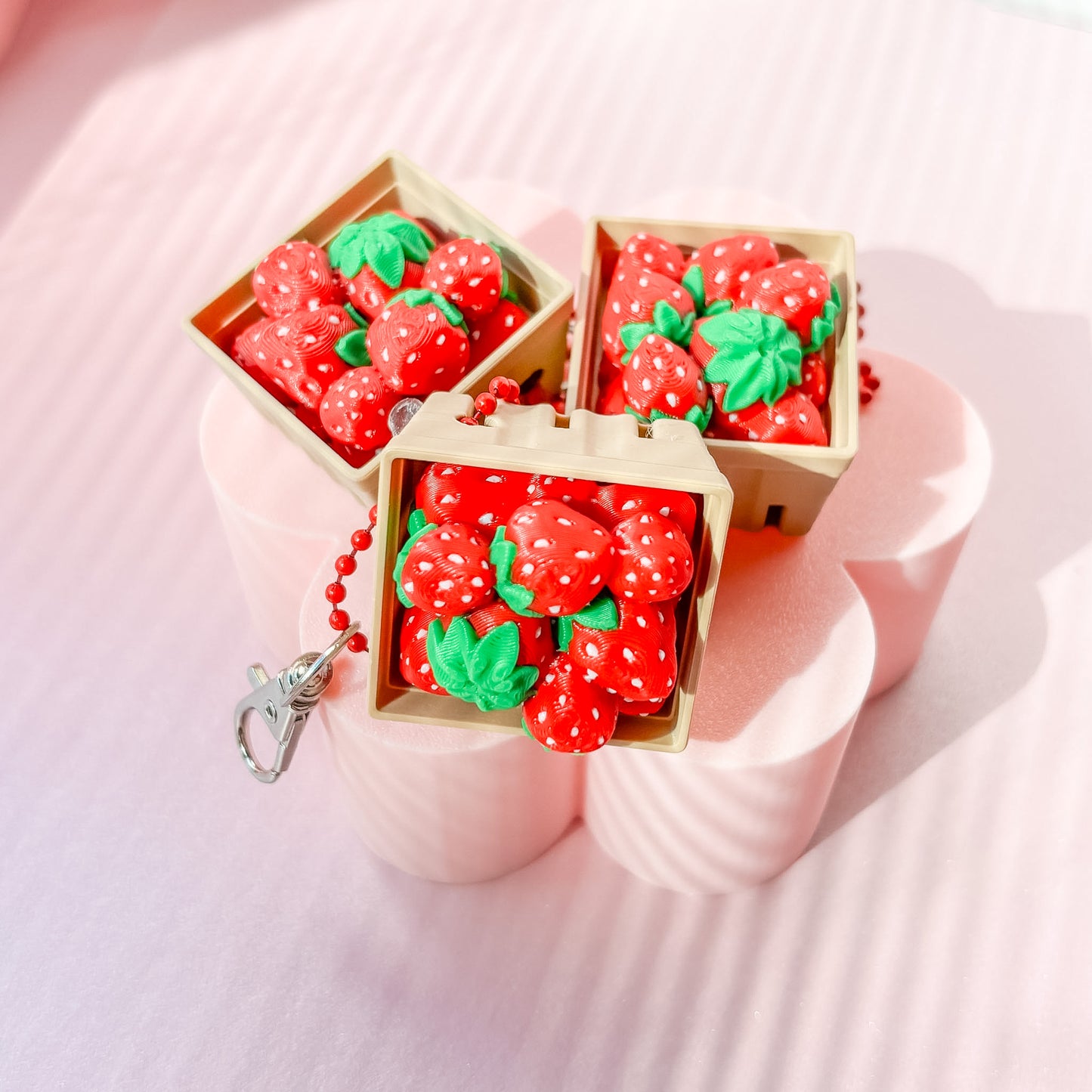 Strawberry-themed fidget clicker on pink stands with 'Frida Bae' branding in the background